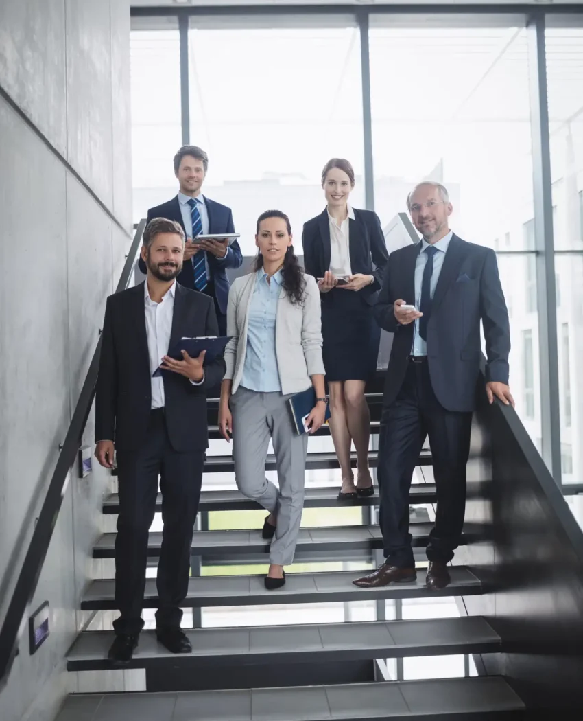 Portrait of confident businesspeople standing on staircase in office